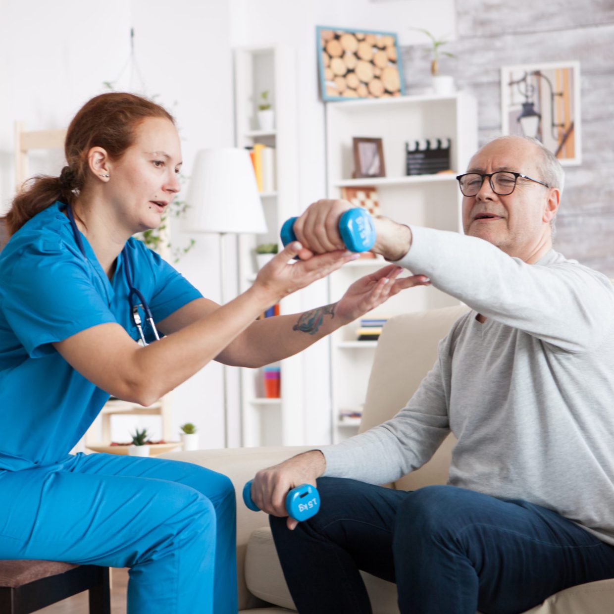 Senior man in nursing home with doing physical therapy Senior man in nursing home with doing physical therapy with help from nurse using dumbbells.